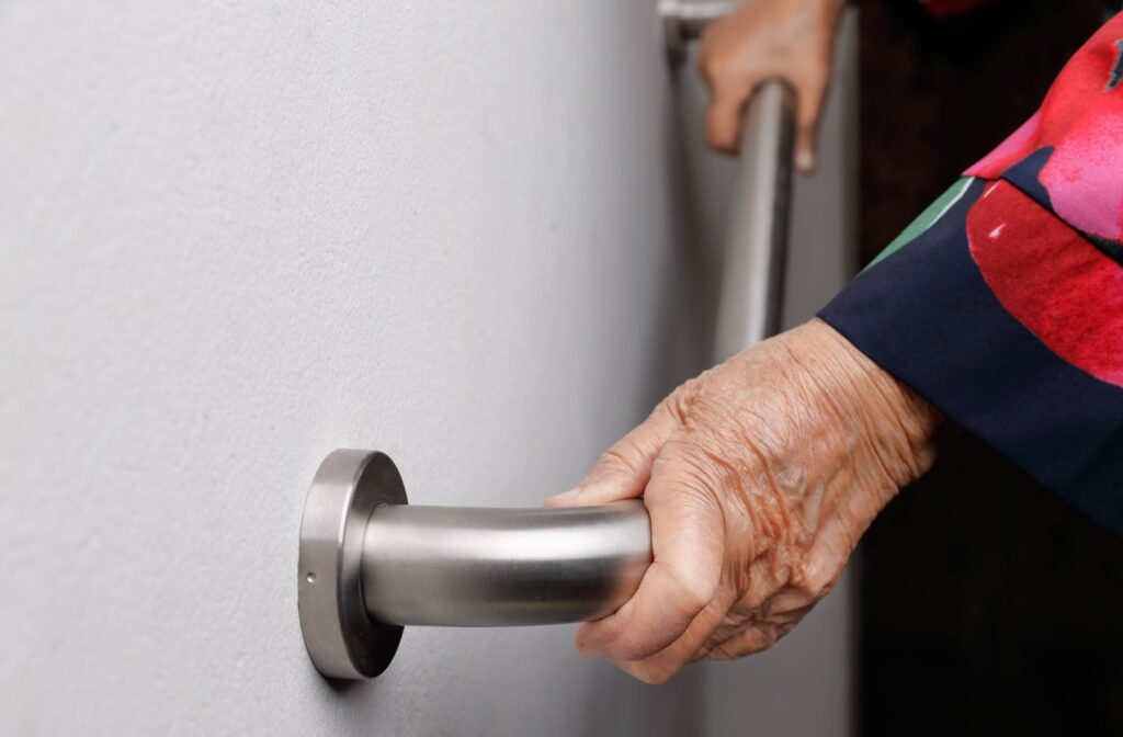 Close-up of an older adult woman’s hand holding on a handrail for safety walk steps.