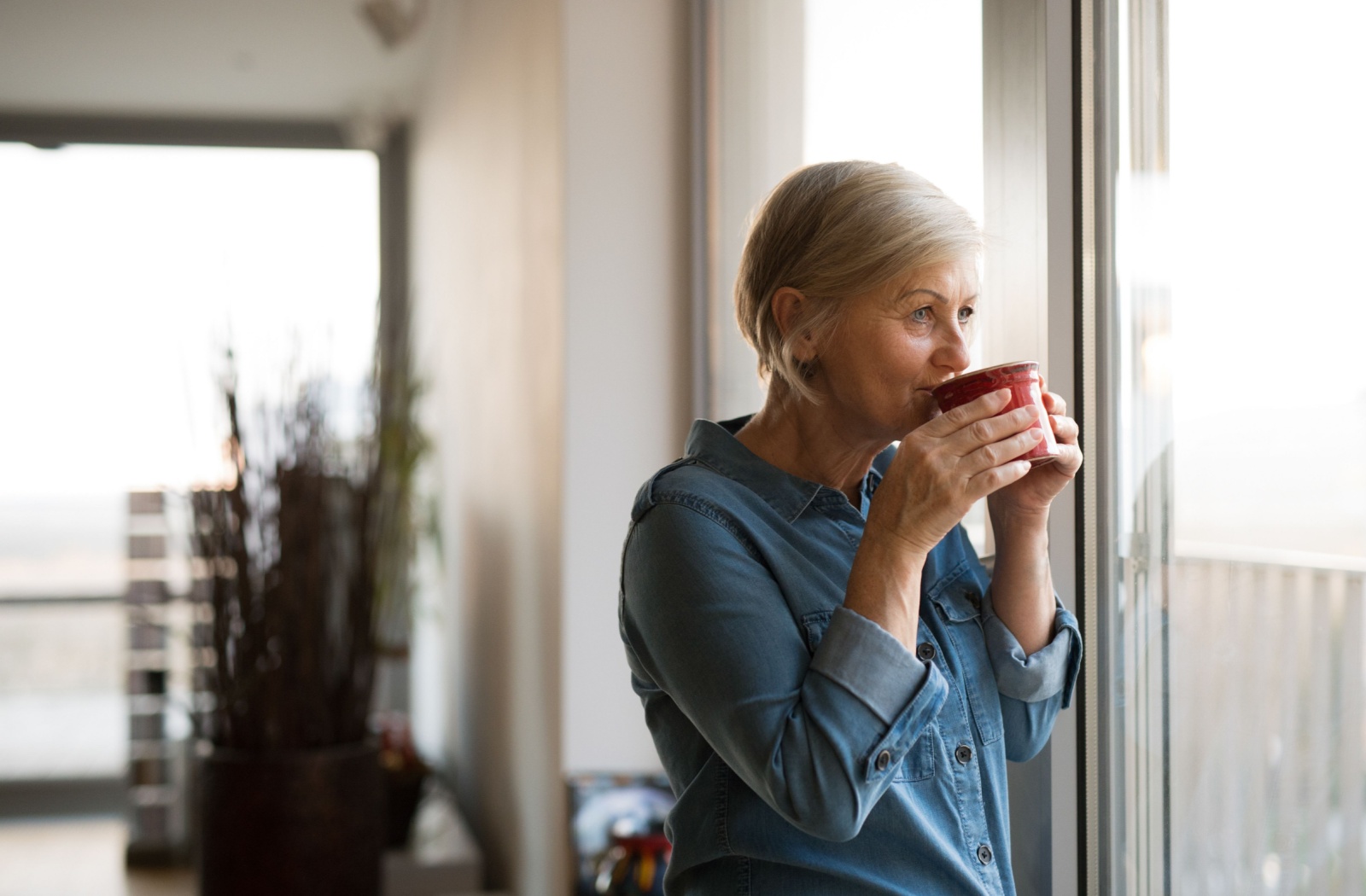 Senior woman enjoying a cup of coffee at a window.