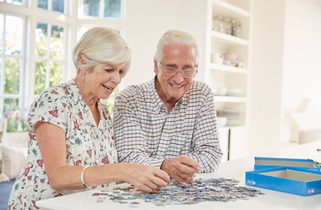 A smiling senior couple enjoys an afternoon solving a puzzle together.