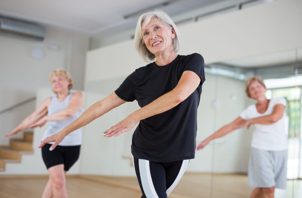 Older adults smile while they participate in a dance class for exercise.