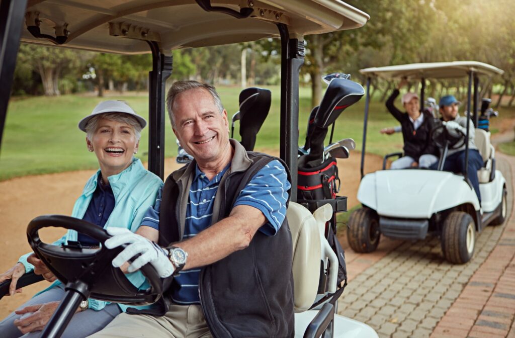 A group of seniors drive their golf carts down a path on a course.