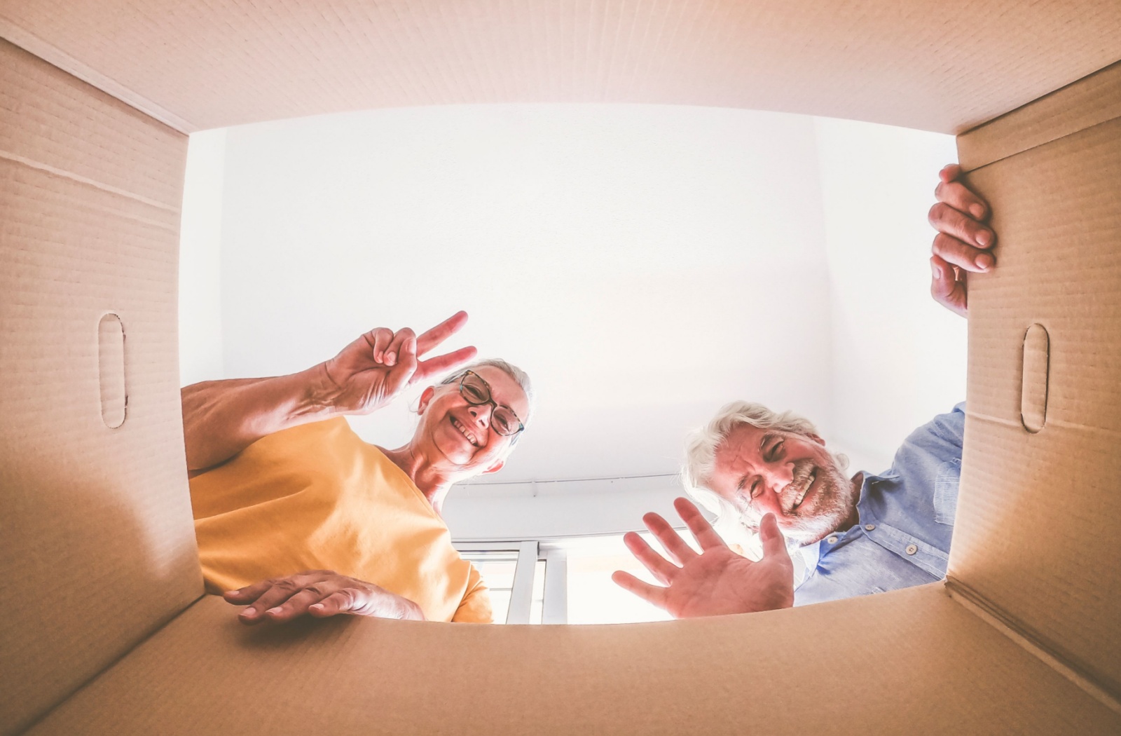 An image from the inside of a box looking up at an older couple as they pack for a move.