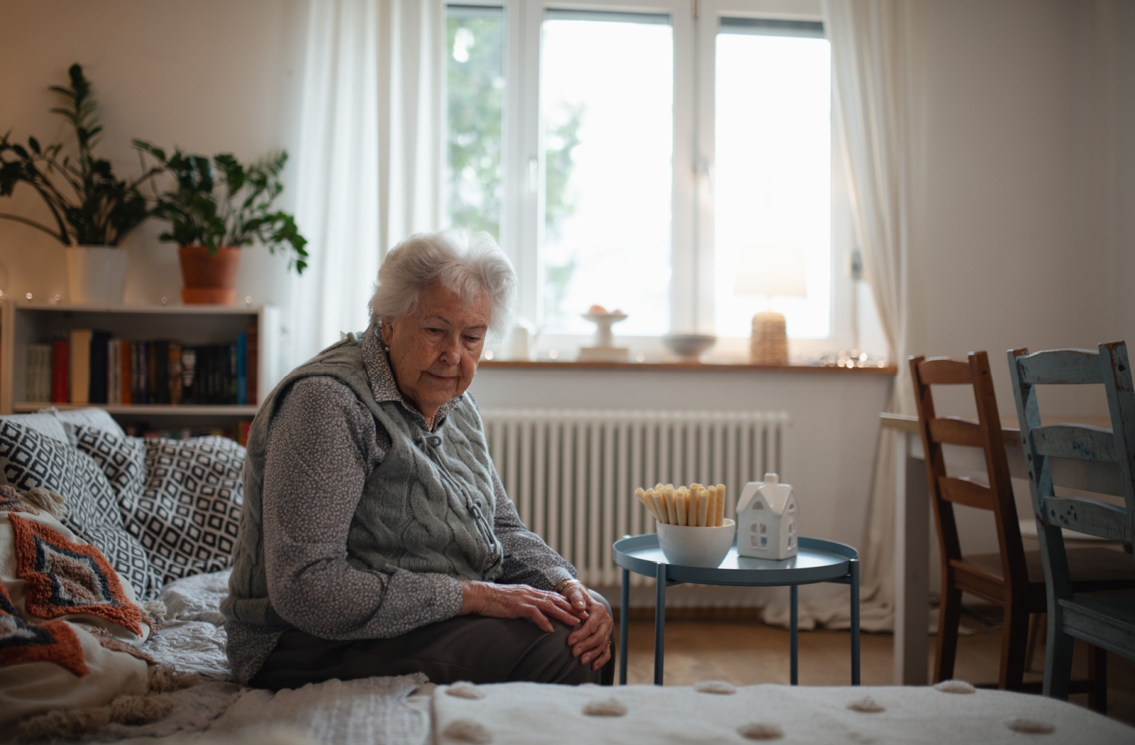 A lonely senior looks at their empty couch in their empty home, wishing they had more company or people to be around