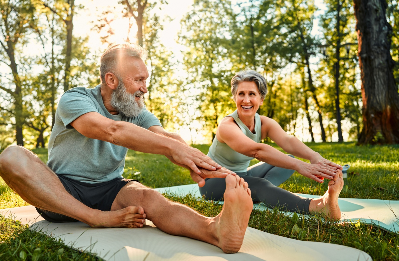 A senior couple each do a hamstring stretch while outdoors after exercising to help their bodies recover from exercise
