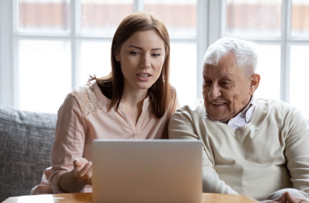 An adult uses a computer as an aid to show their senior parent assisted living options in their community