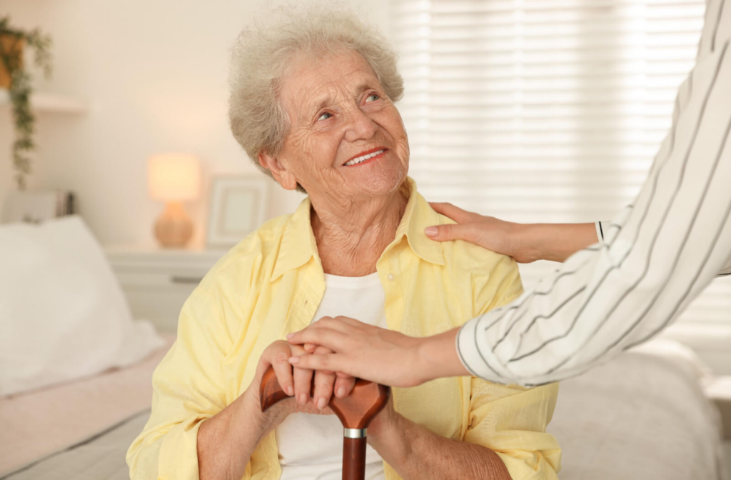 An appreciative resident in assisted living smiles at an out-of-frame caregiver while preparing to get up from their bed